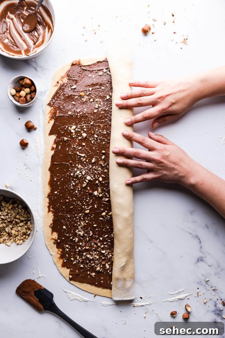Nutella Babka Recipe: Chocolate-Hazelnut Swirl Loaf 8 overhead view of a person roling the babka dough into a log