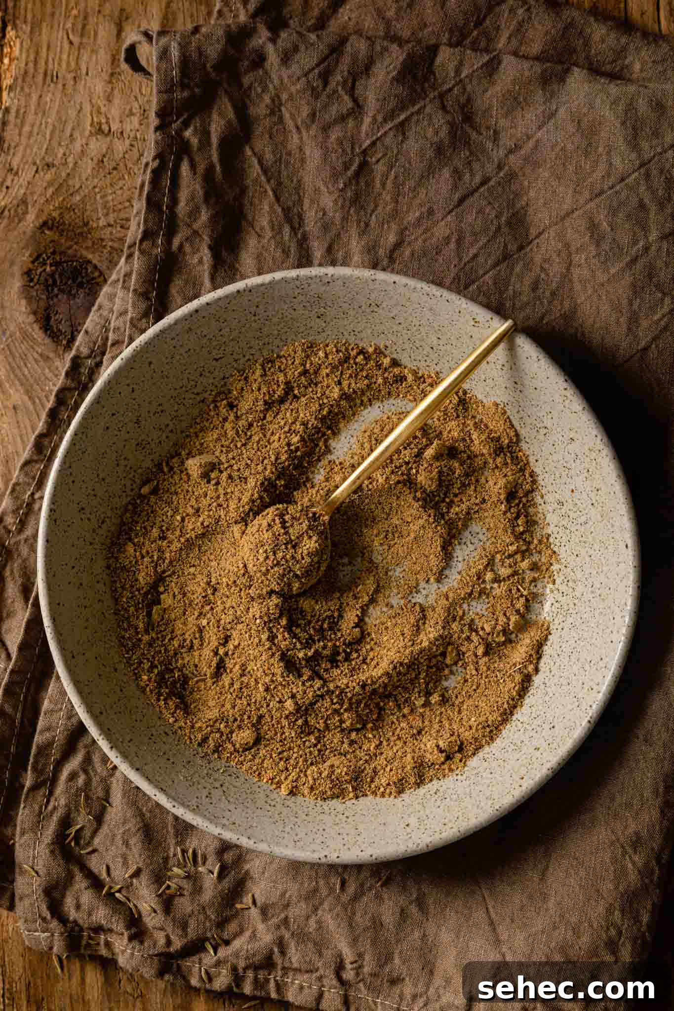 Authentic Chaat Masala Recipe: Homemade Indian Spice Mix 2 Chaat Masala inside a speckled bowl with a golden spoon inside