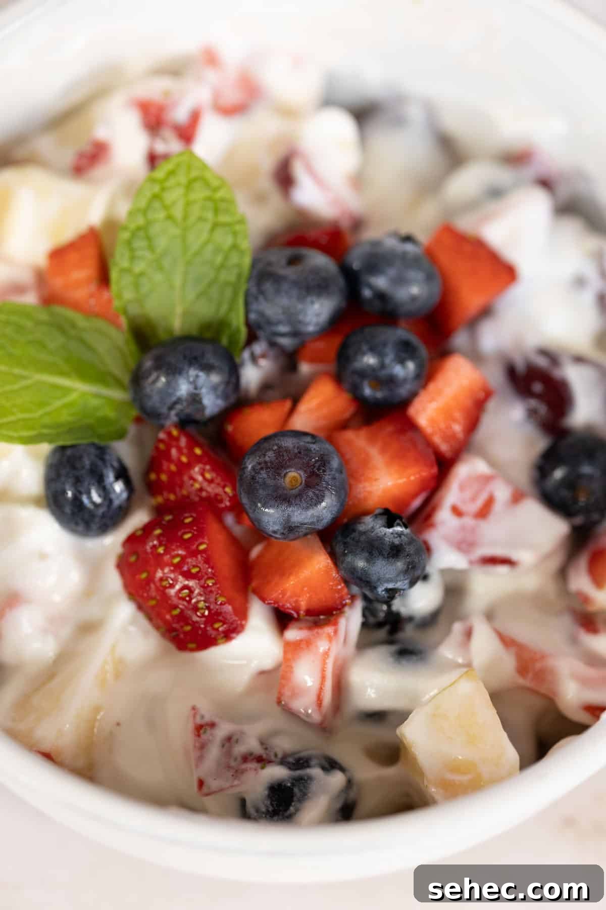 Creamy fruit salad with blueberries and strawberries.