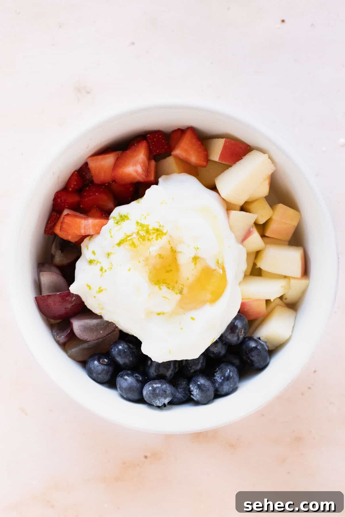 A bowl filled with fruit topped with yogurt and lime zest.