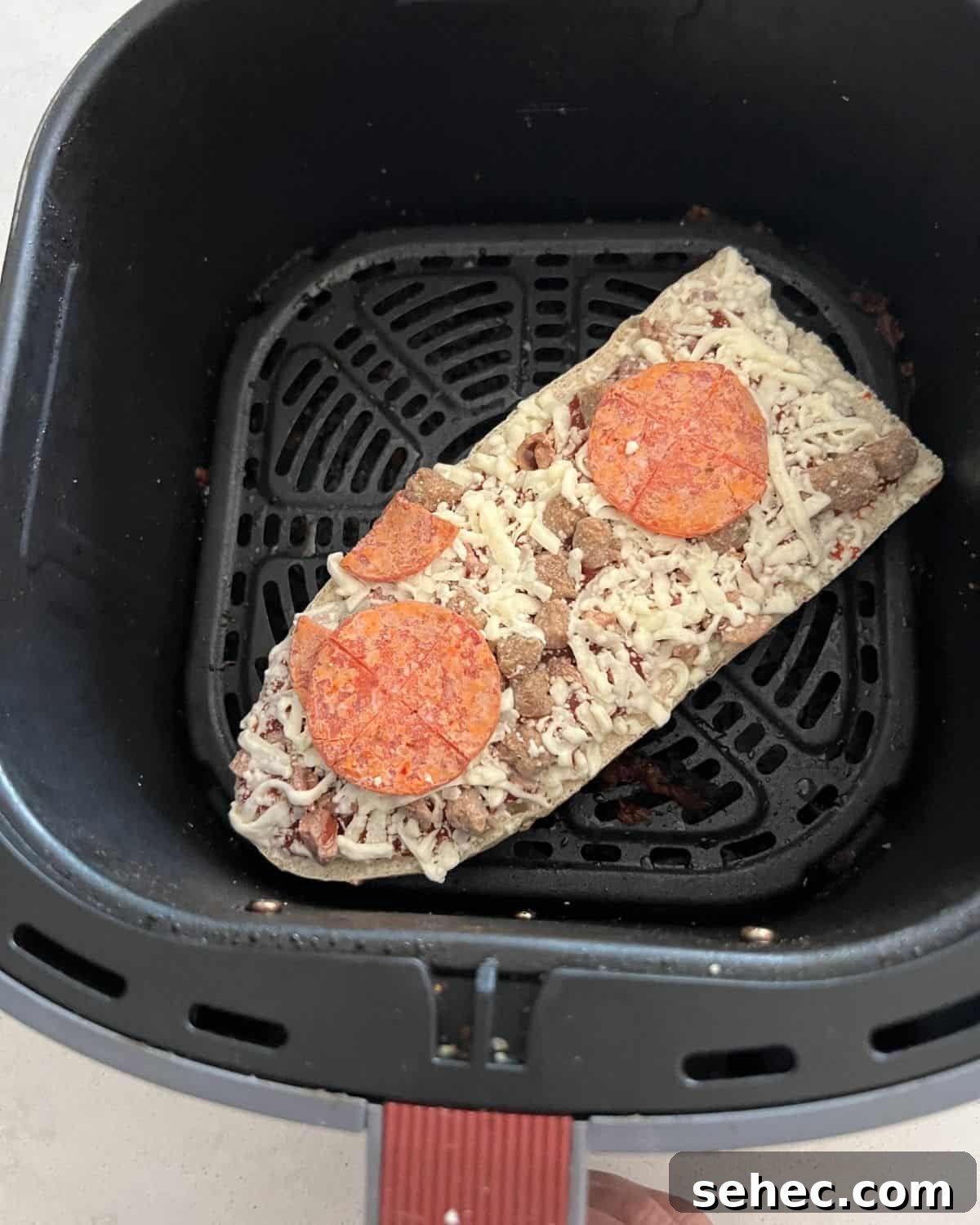 Frozen Red Baron pizza in air fryer basket.
