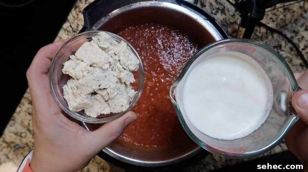 Adding herb cheese and cream to pot.
