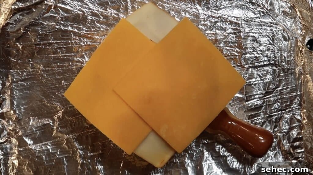 Adding cheddar cheese on top of muenster cheese.
