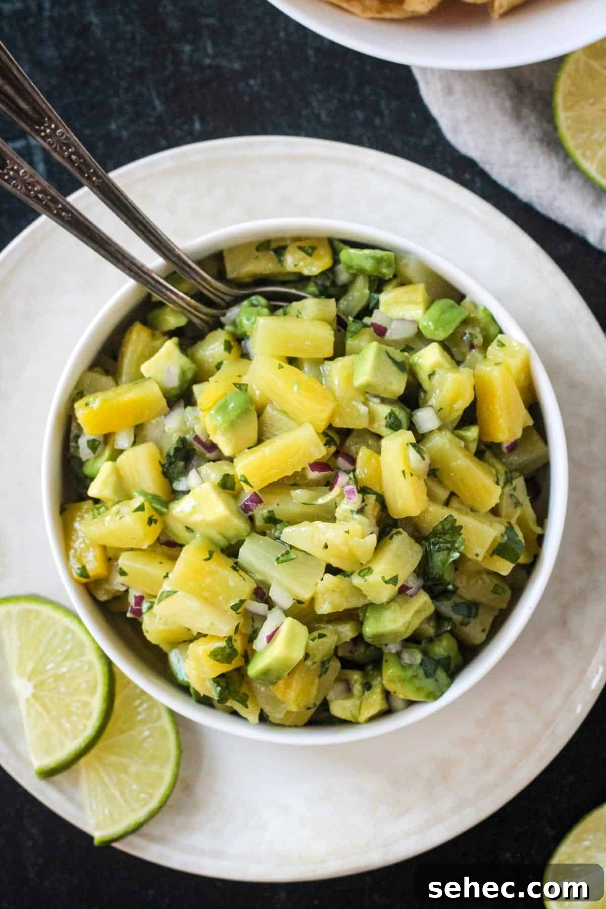 Fresh Pineapple and Avocado Salsa with Lime 11 Pineapple avocado salsa in a serving bowl with two spoons.