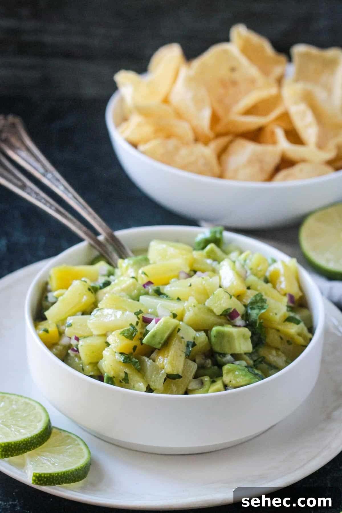 Fresh Pineapple and Avocado Salsa with Lime 7 Diced pineapple and avocado salsa in a white bowl in front of a bowl of tortilla chips.
