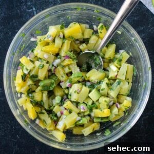 Fresh Pineapple and Avocado Salsa with Lime 8 Diced pineapple, avocado, cilantro, and red onion mixed in a bowl.