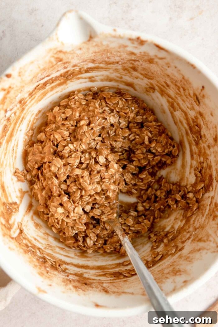 Oatmeal crumble topping mixture mixed up in a mixing bowl with a spoon in it.