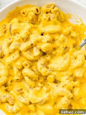 A bowl of dairy free Mac and cheese with a spoon in it.
