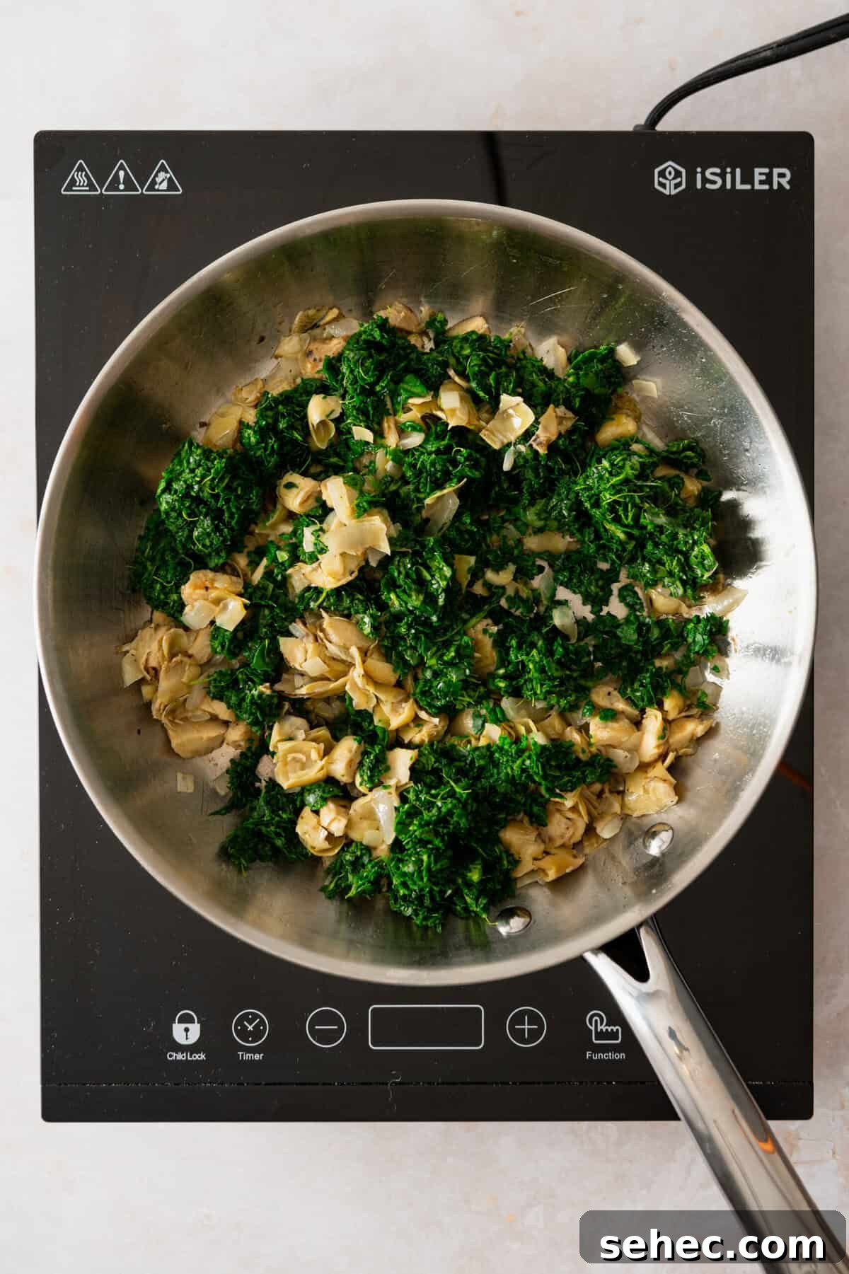 A pan with chopped artichoke hearts and spinach in it.